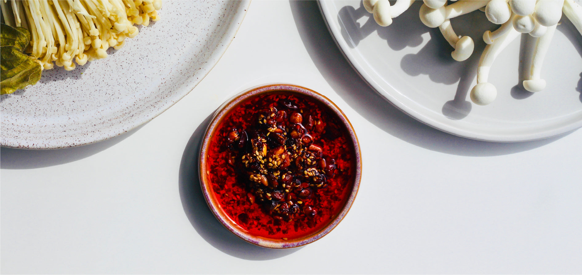 Two big white plates contain different types of mushrooms. A small round dish in the middle contains White Mausu peanut Rāyu
