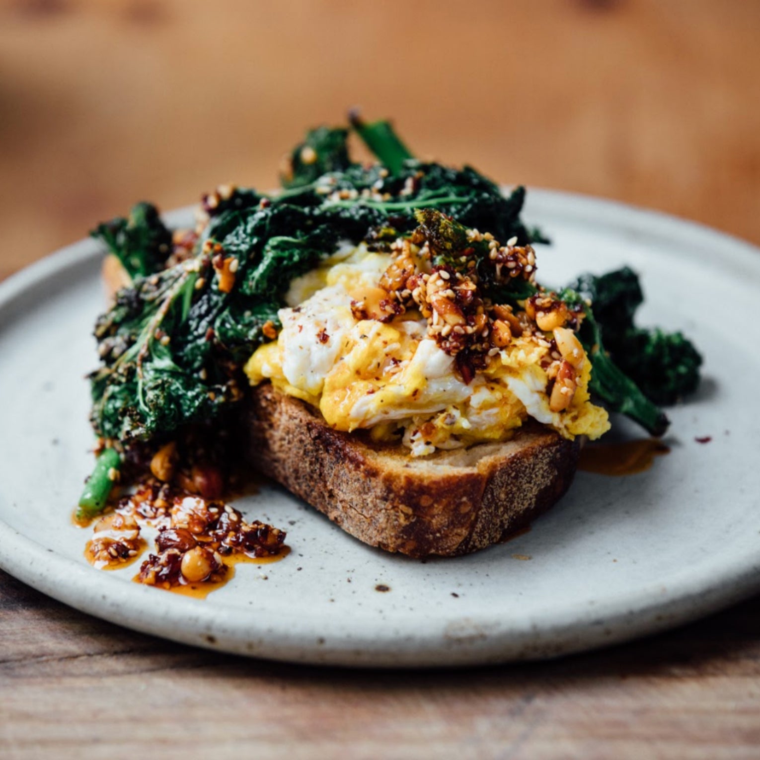 A plate with sourdough toast covered in cheesy scambled eggs and kale with White Mausu Peanut Rayu
